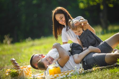 Cheerful family having picnic. Parents having dinner with their kids outdoors.